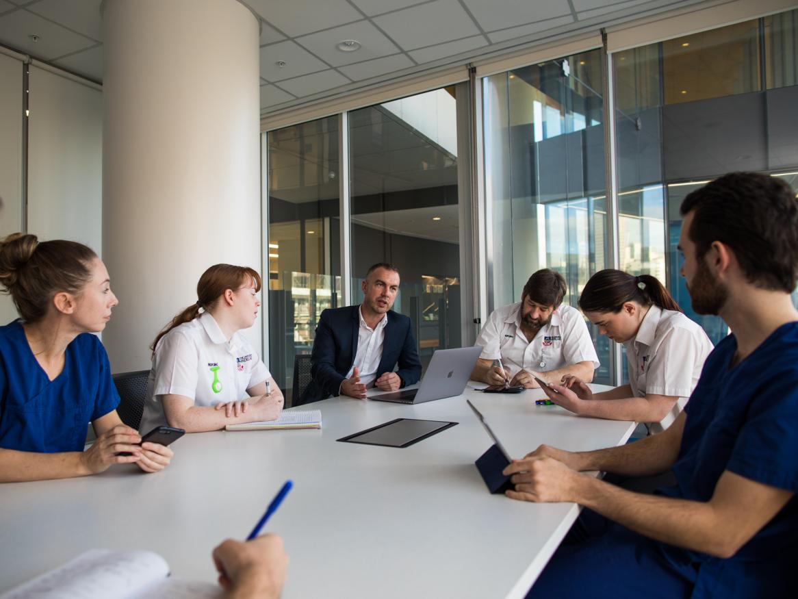 Adam Montagu talking to a group of students and colleagues at a large table