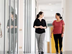 Female research study participant and female researcher walking down corridor, having conversation