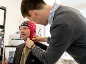 Male research study participant being fitted with skull cap by male researcher
