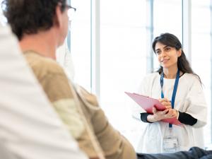 Female researcher talking to male trial participant, who is lying in a bed
