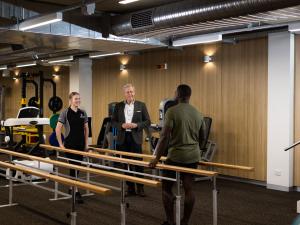 Image of people taking next to parallel bars in rehab gym