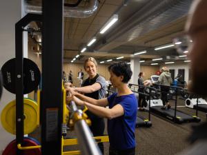 Image of physio student helping lady at a bar in the rehab gym