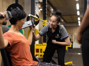 Image of physio student helping patient with weights in rehab gym