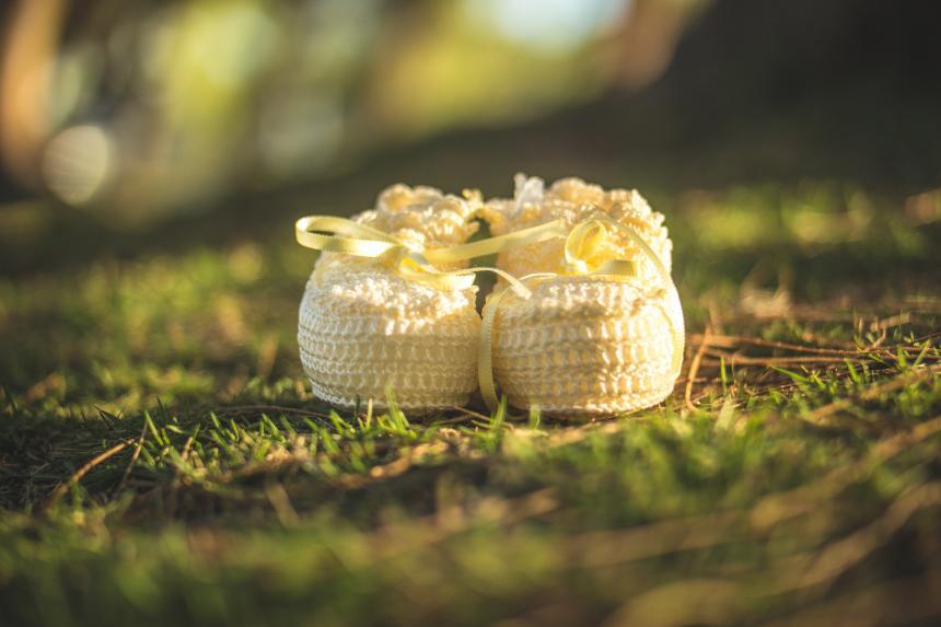 A pair of yellow baby booties placed on grass