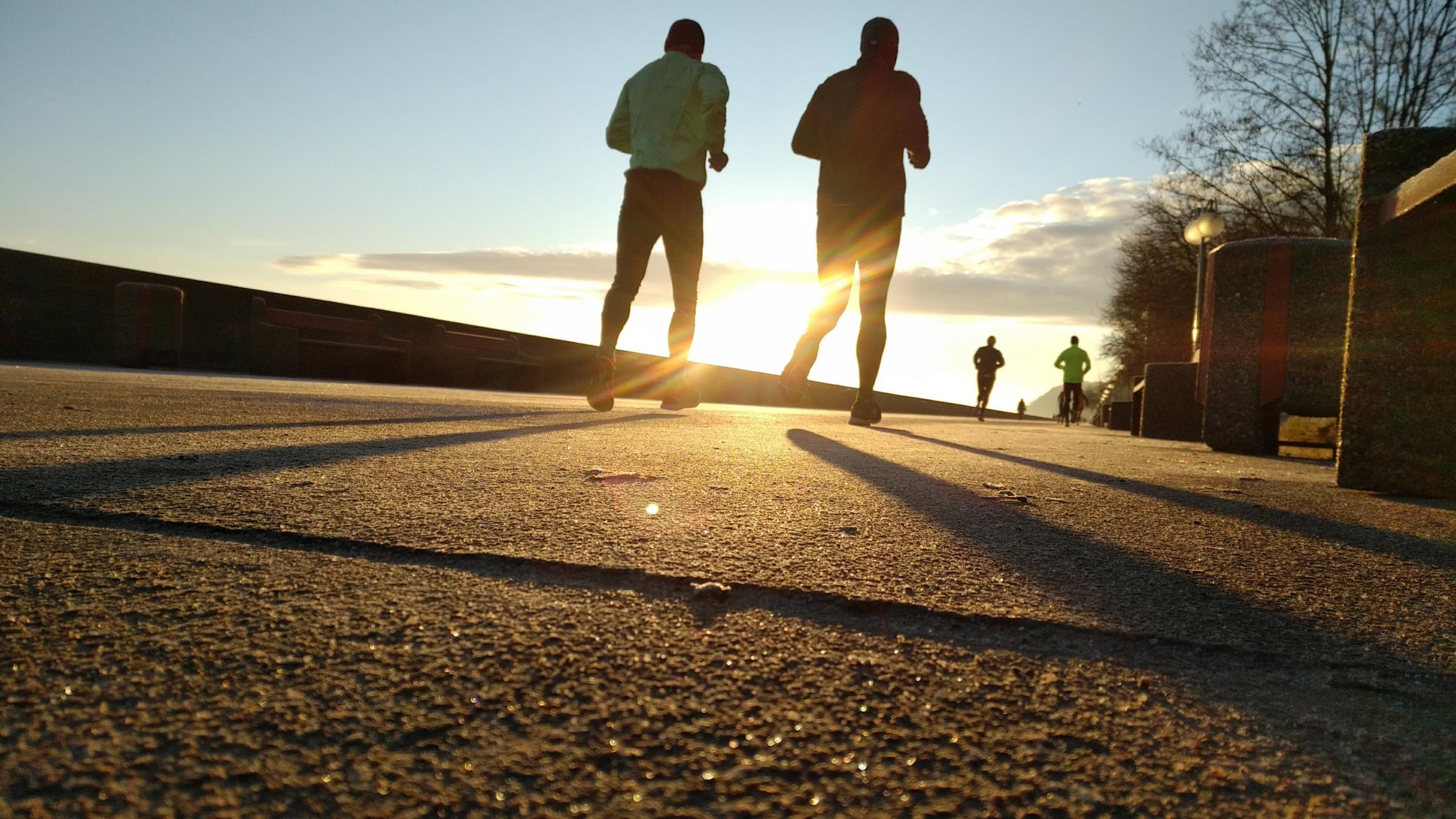 Joggers running on a path at sunrise