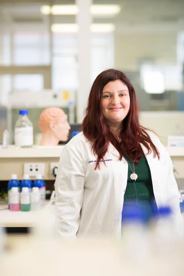 Portrait of Associate Professor Lyndsey Collins-Praino with laboratory in background