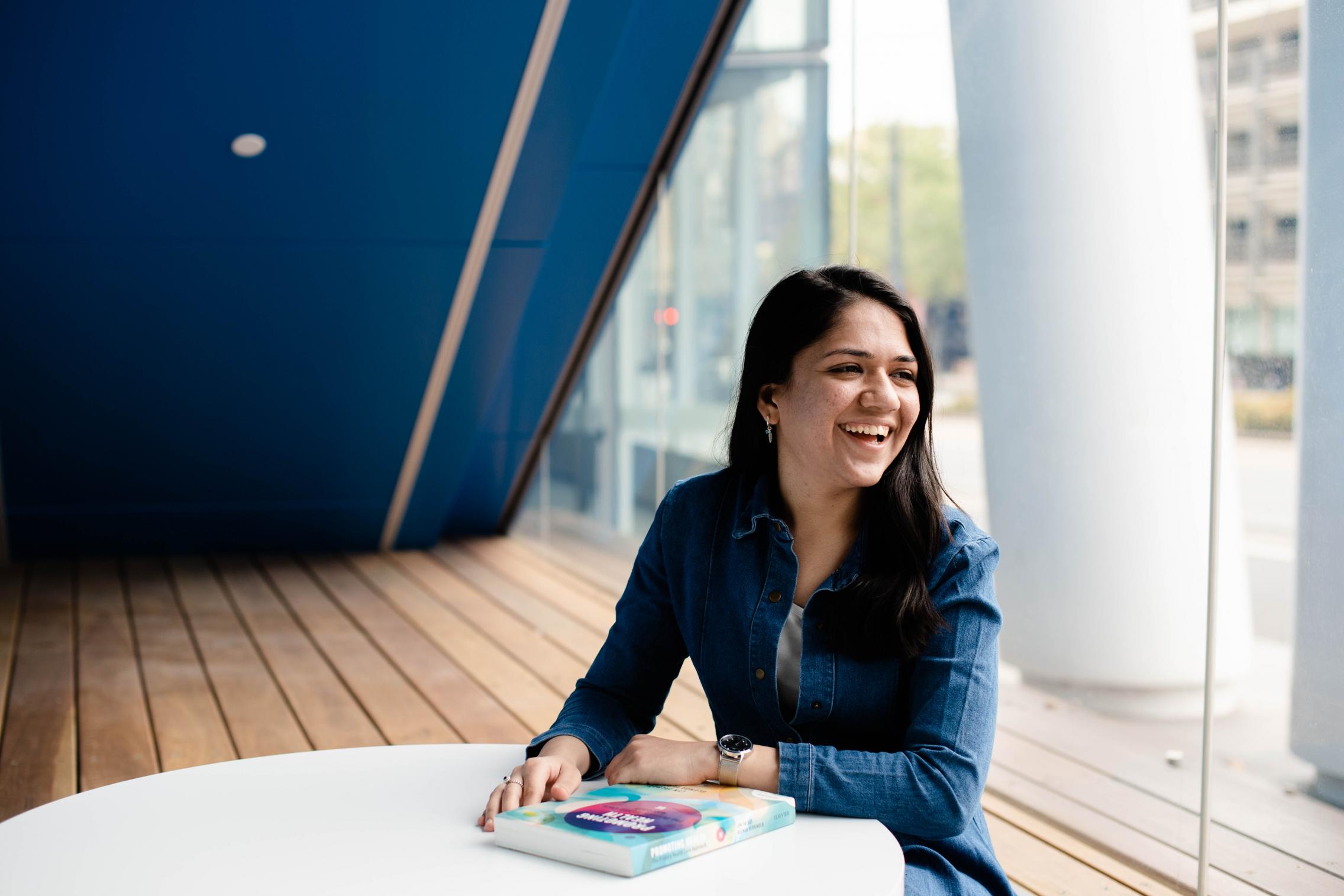 Image of Neha sitting at a desk with a textbook