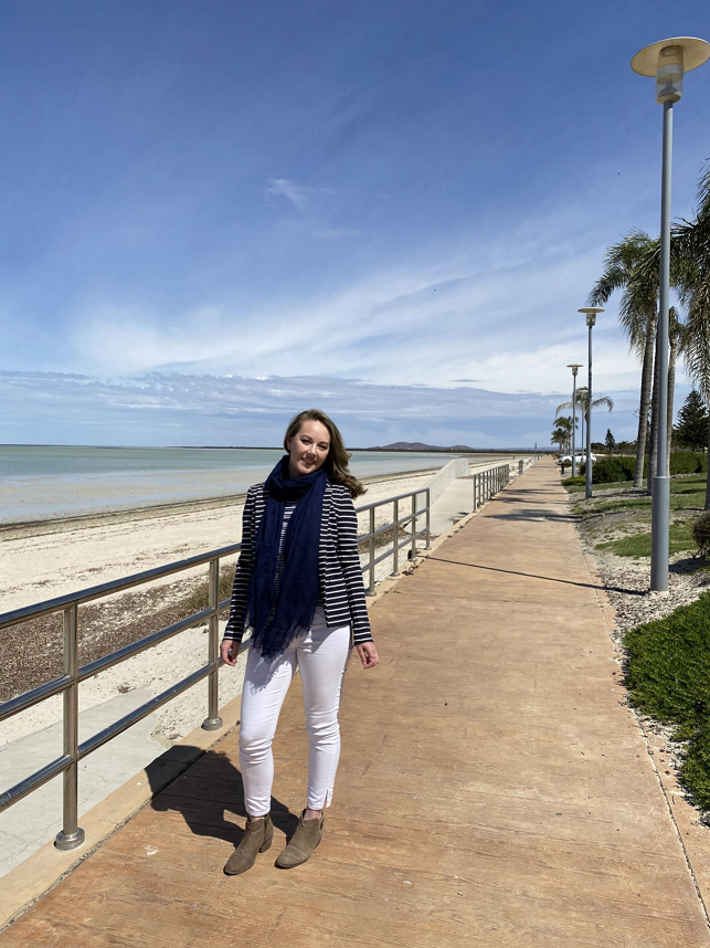 Kyla Burman standing next to handrail by the beach