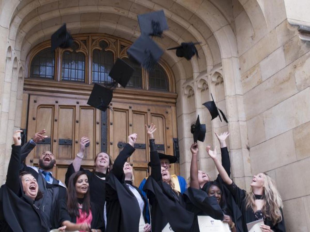 graduations throwing caps into the air after graduation ceremony, on the steps of Bonython Hall
