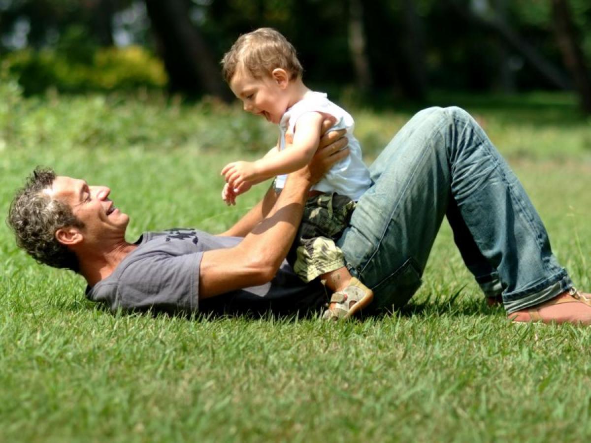 Father playing with infant son on the grass