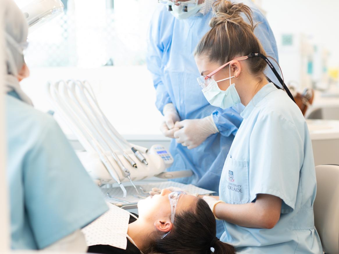 Student dentist assessing dental patient while being observed by teacher