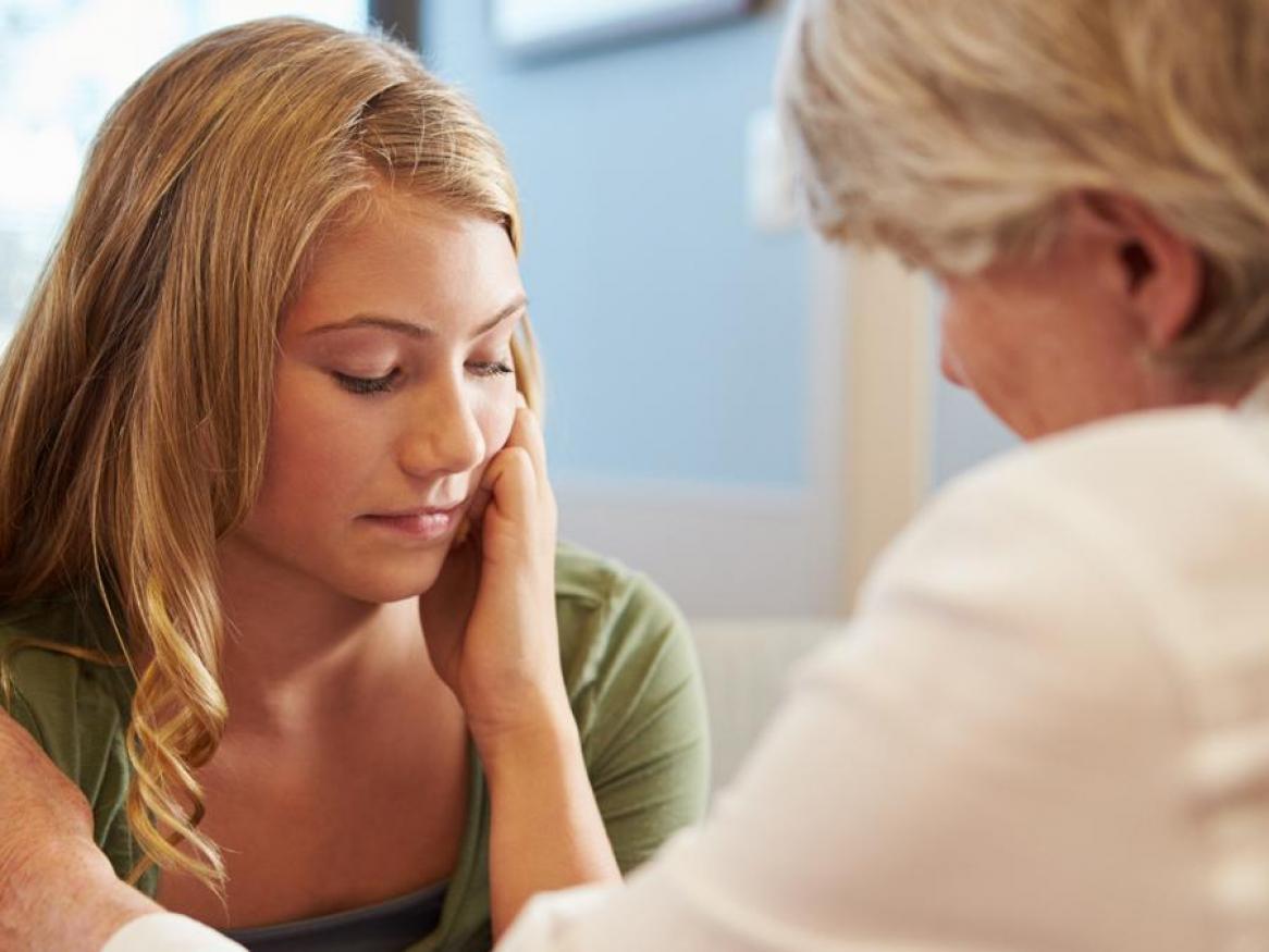 Counsellor supporting young female patient who looks sad