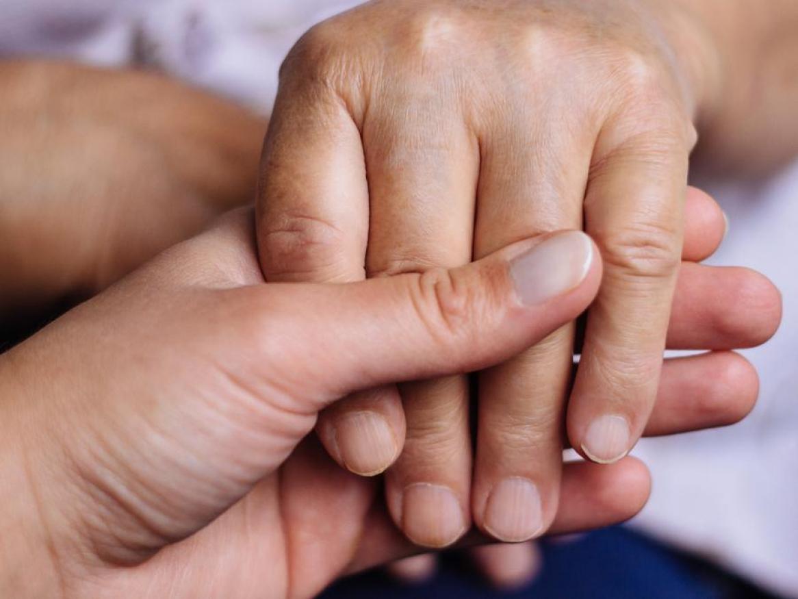 Close up of one hand holding another hand in comfort
