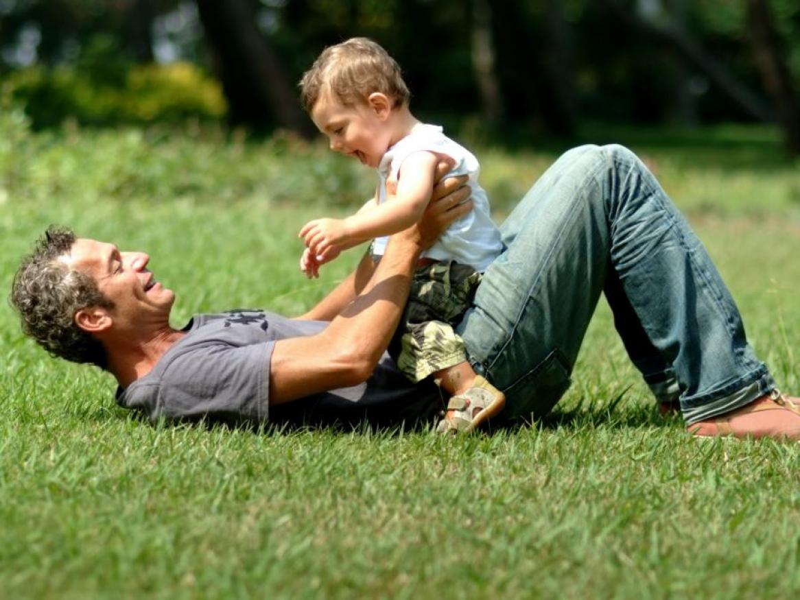 Father playing with infant son on the grass