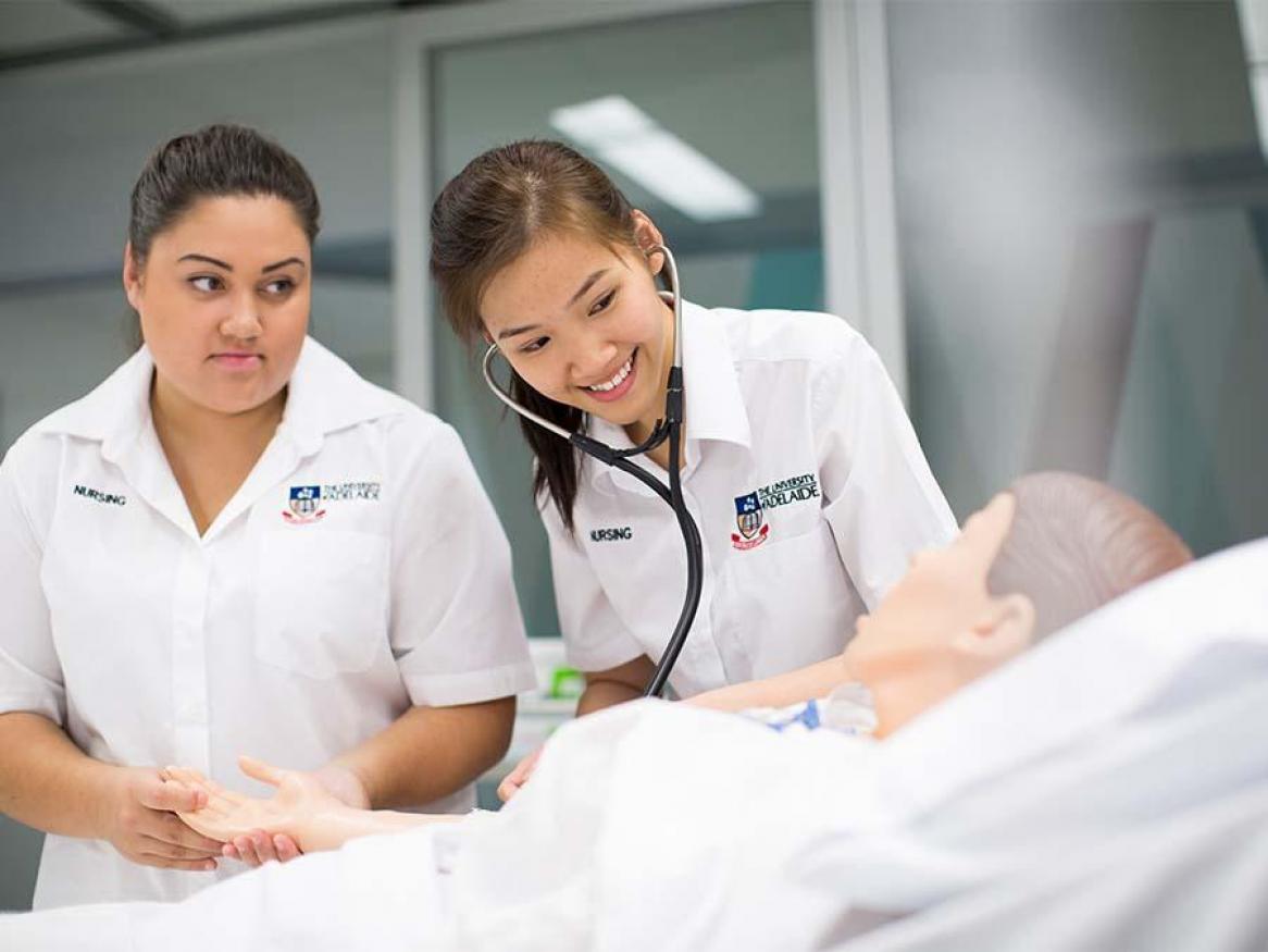 Two nursing students monitoring a simulated patient