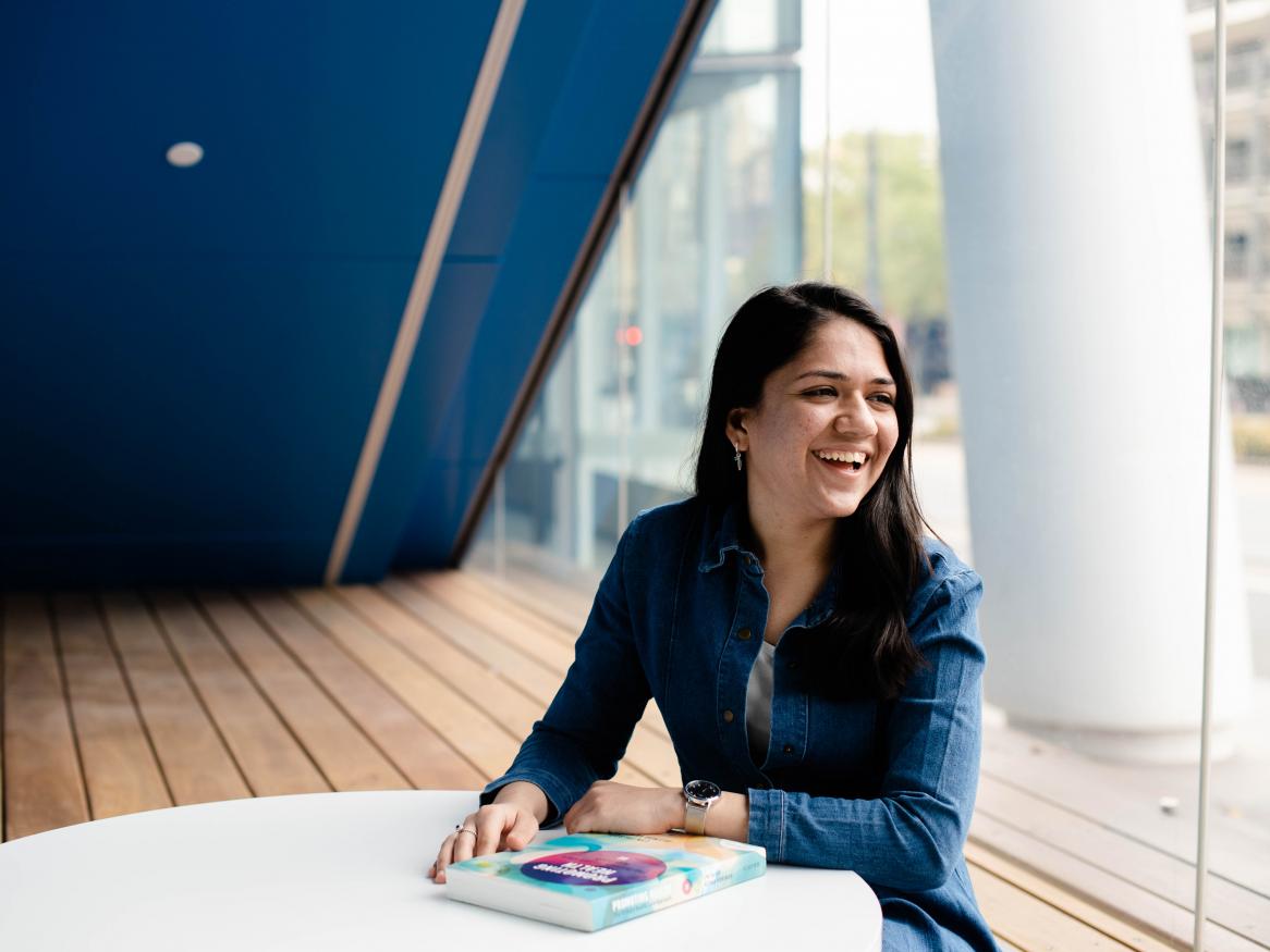 Image of Neha sitting at a desk with a textbook